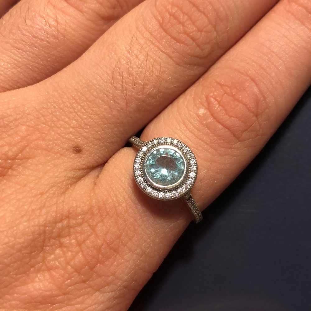 Silver tone ring with round cut blue gem.